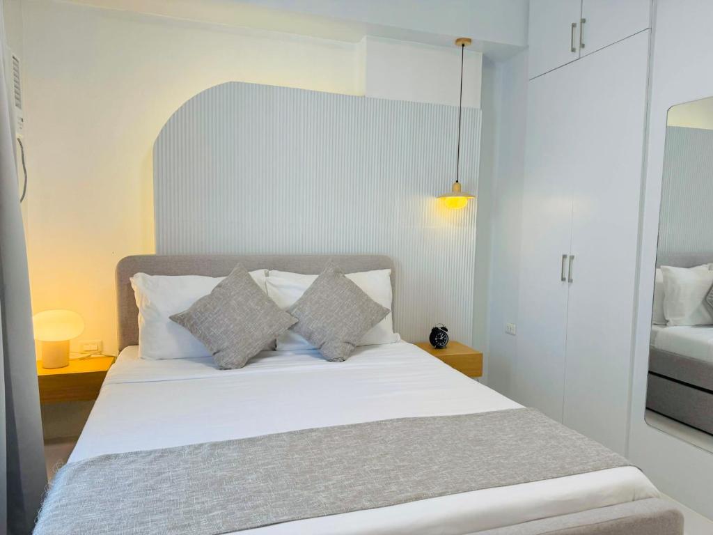 ein Schlafzimmer mit einem Bett mit weißen Laken und Kissen in der Unterkunft Simple White Scape at Mesavirre Bacolod in Bacolod City