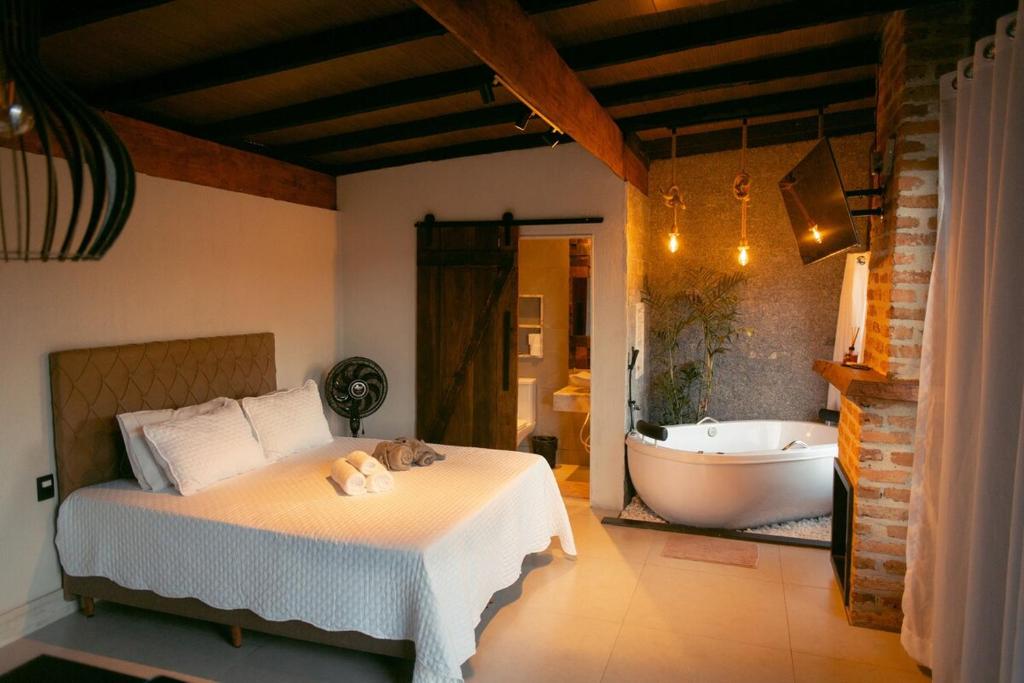 una camera da letto con un letto e una vasca da bagno di Herança do Vovô02 a Domingos Martins