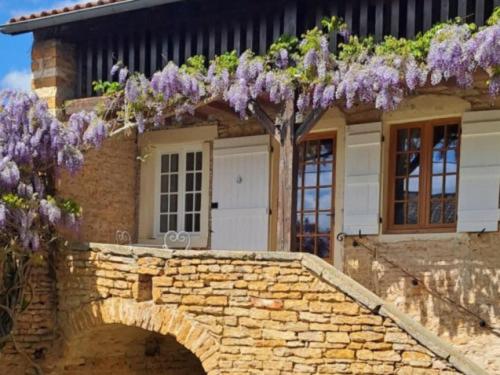 Saint-PointにあるLa Chenevièreの石橋の上の紫色の花が咲いた家