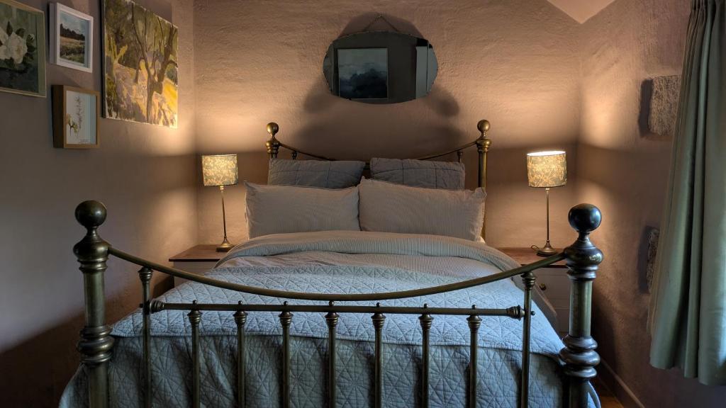 een slaapkamer met een bed met 2 lampen en een spiegel bij The Hideaway in Falmouth