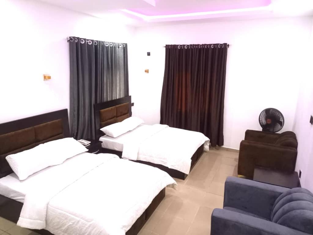 Un dormitorio con dos camas y un sofá. en Divine Villa and Resort Guest House PLOT 35 Umuezeukwu Road, Oboro, Ikwuano LGA,Abia State, 
