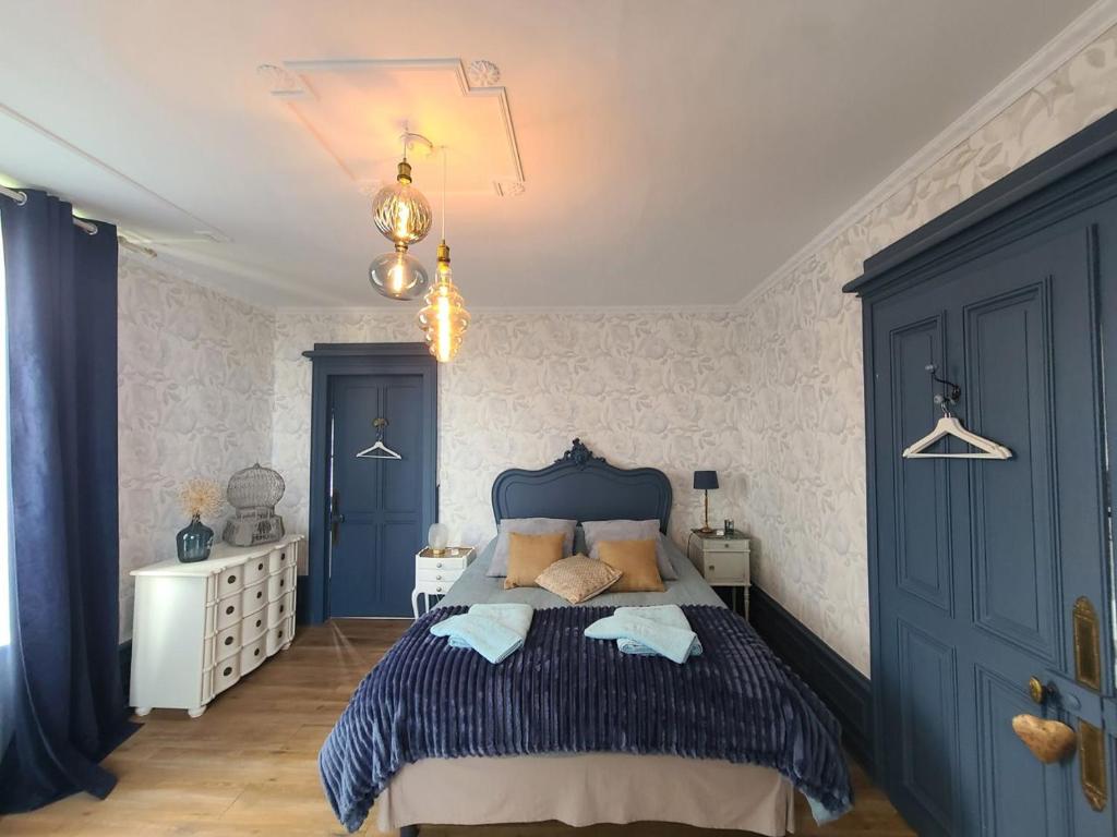 a bedroom with a blue bed and white walls at MAISON YLANG in Médonville