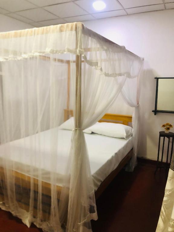 a bedroom with a canopy bed with white curtains at Chill corner in Ahangama