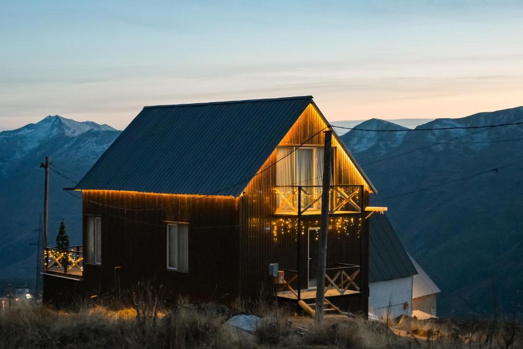 a house on a hill with mountains in the background at Snow Heaven for 10 in Gudauri