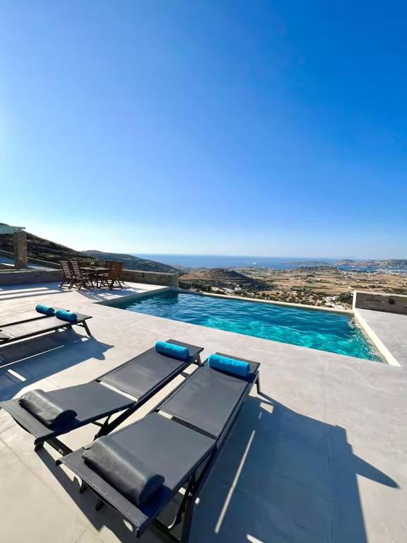 a swimming pool with two lounge chairs and the ocean at Villa House Theasis in Kampos Paros