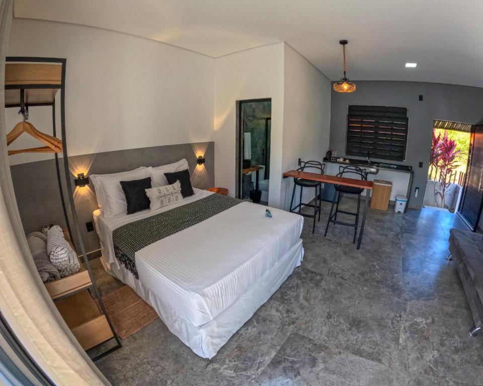a bedroom with a large white bed and a desk at Pousada Mon Gâté in Japaratinga