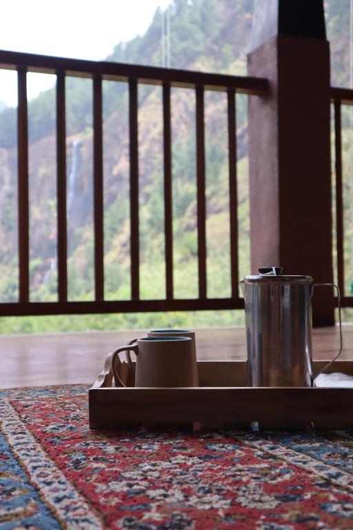a tray with a tea kettle on a rug with a window at Pekoe Bungalow Bambarakanda Waterfall and Pekoe Trail Retreat in Welegama