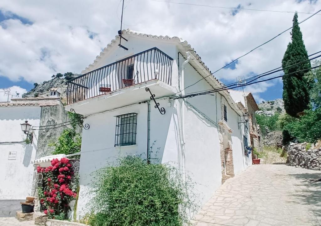 a white house with a balcony on a street at Casa Lola in Benaocaz