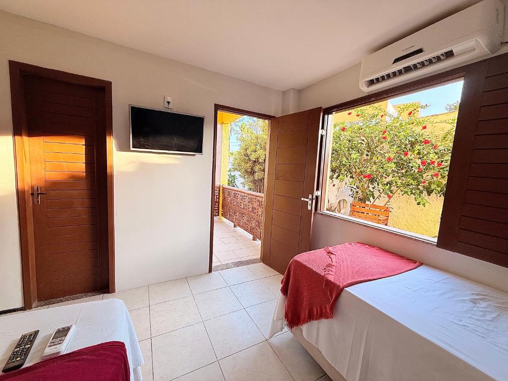 Un dormitorio con una cama y una ventana y un televisor. en Pousada Sunrise Beach Cumbuco, en Cumbuco