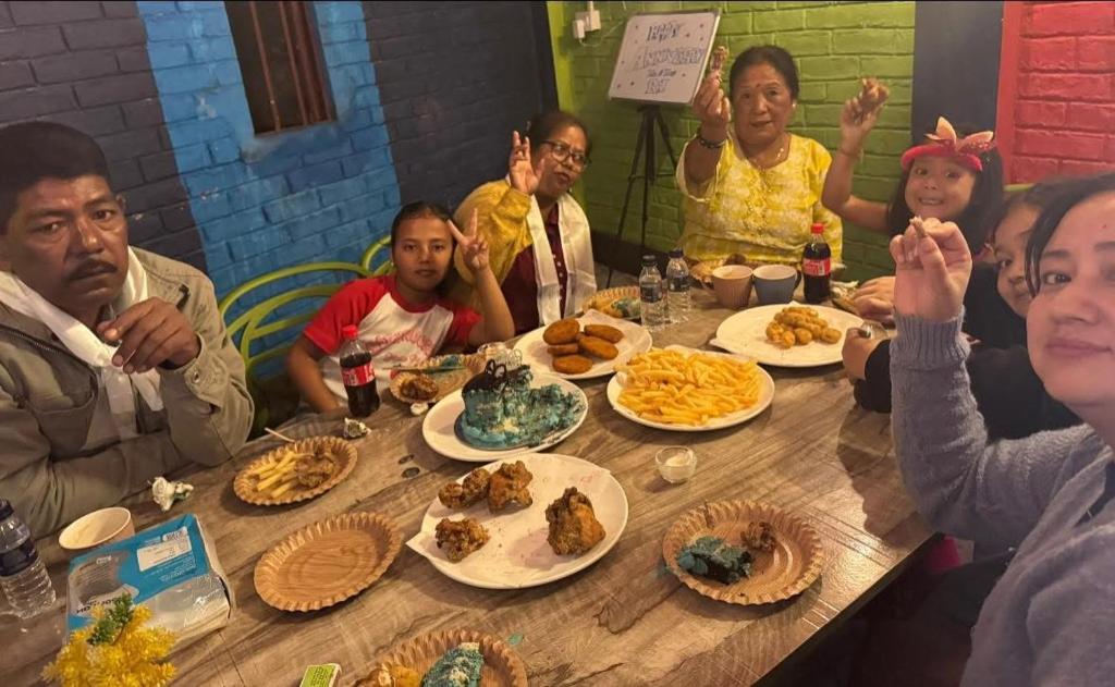 Un groupe de personnes assises autour d'une table avec de la nourriture dans l'établissement Green Hill Home, à Darjeeling