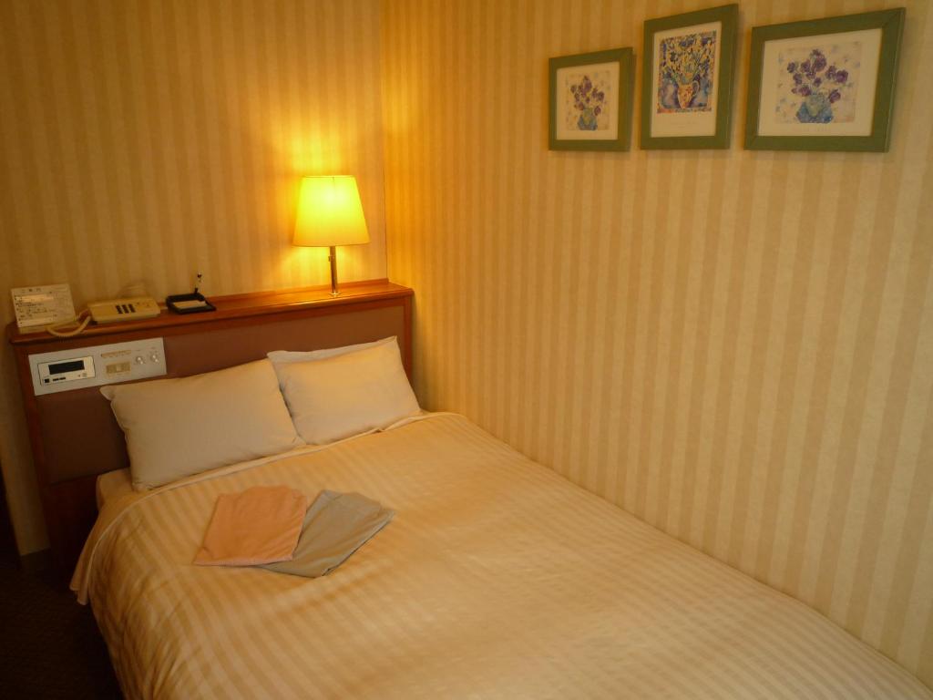 a hotel room with a bed with a towel on it at Hotel Crown Hills Koriyama in Koriyama
