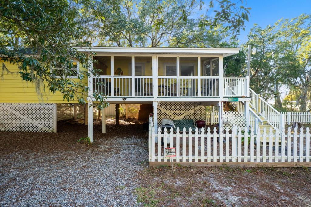 a small yellow house with a white fence at Bay Leave in Gulf Shores