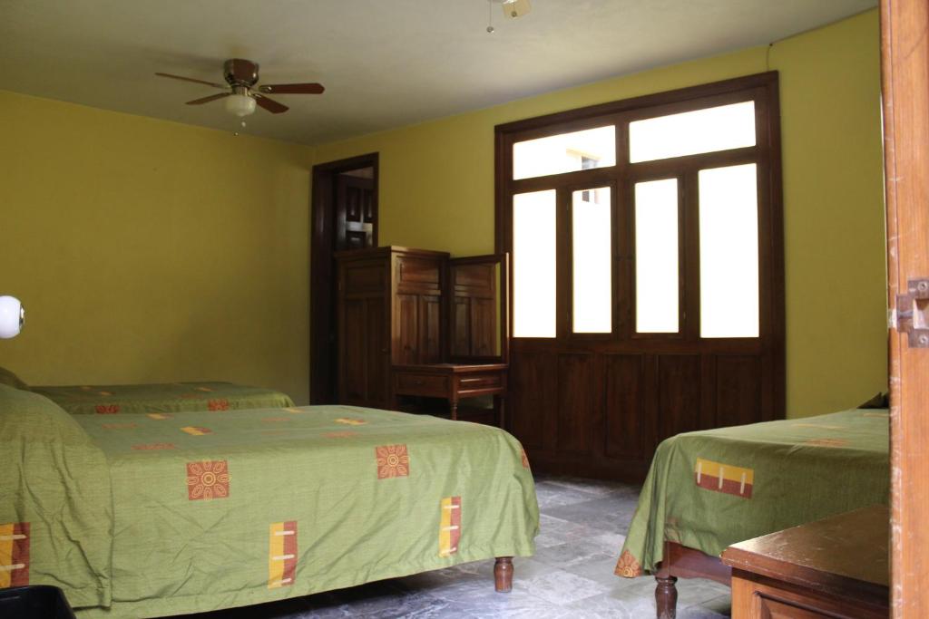 a bedroom with two beds and a window and a door at Hotel Camino de Villaseca in Guanajuato