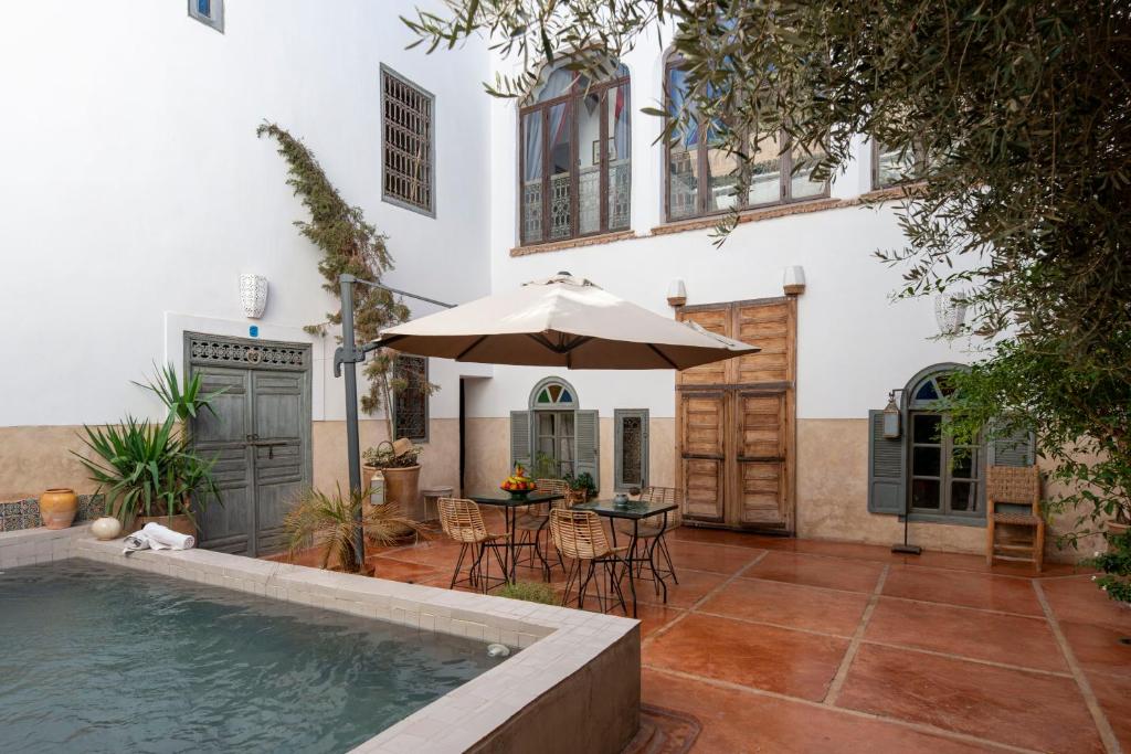 une cour avec une piscine et un parasol dans l'établissement Riad le Jardin de Mina, à Marrakech