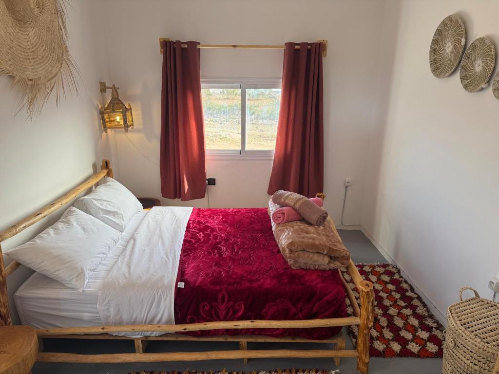 a bedroom with a bed with red curtains and a window at Atlantic refuge rooms in Essaouira