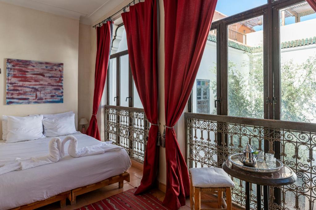 une chambre avec un lit et un balcon avec fenêtres dans l'établissement Riad le Jardin de Mina, à Marrakech