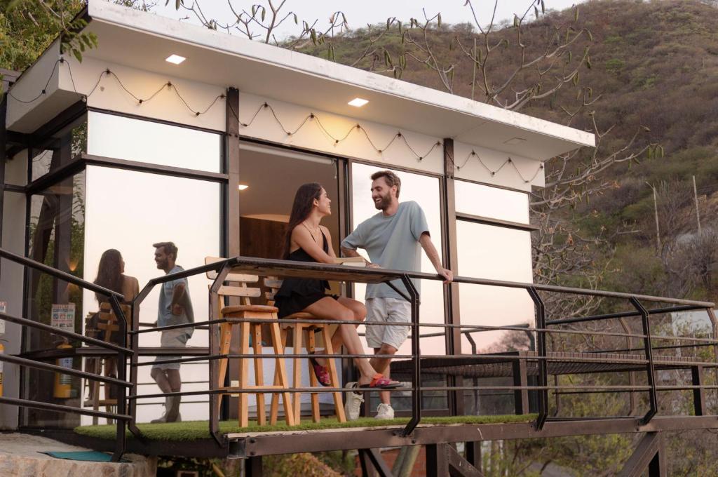 ein Paar steht auf dem Balkon eines winzigen Hauses in der Unterkunft Villa Malibu in Taganga