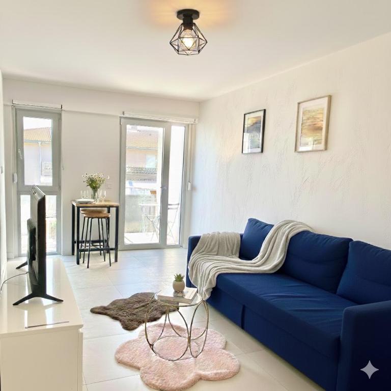 a blue couch in a living room with a table at Cozy studio avec balcon aux portes de Genève in Ambilly
