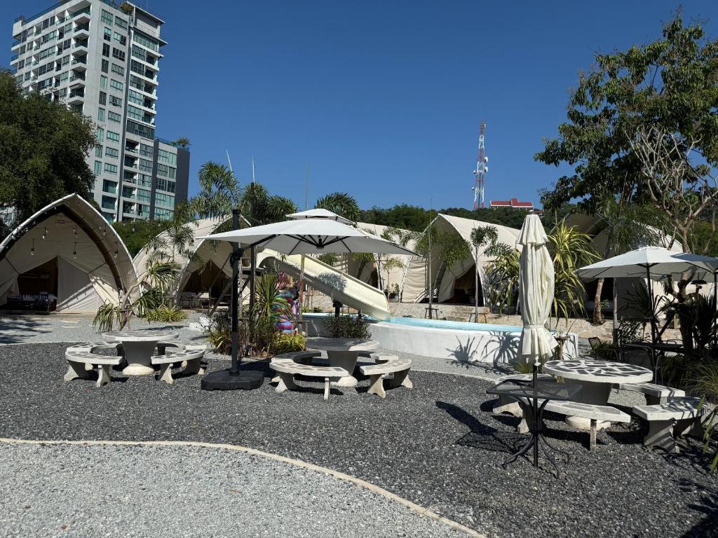 een park met tafels en parasols en een zwembad bij Camping&Cafe in Pattaya South