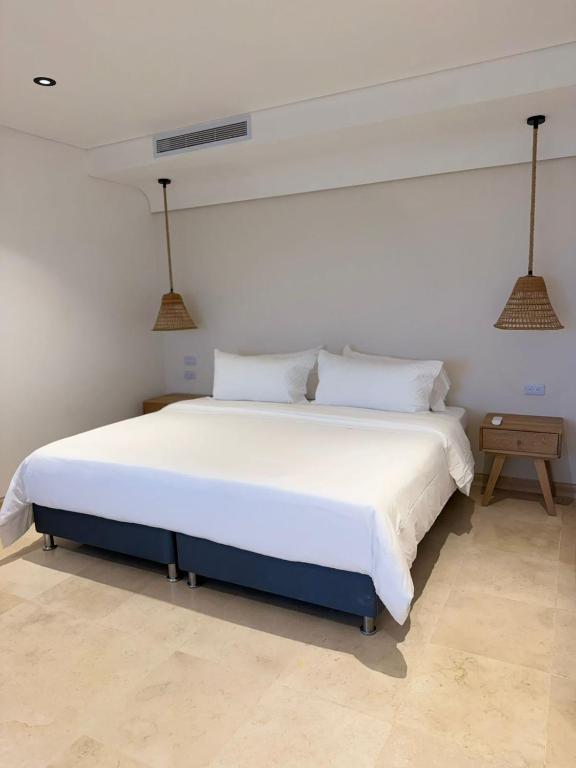 a bedroom with a large bed with white sheets and pillows at Del Mar City View in Cartagena de Indias