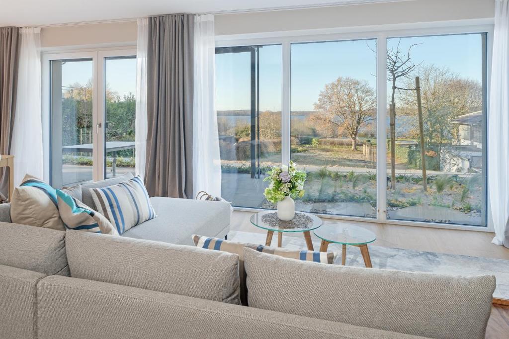 ein Wohnzimmer mit Couch und großem Fenster in der Unterkunft Gollings am See Gingko-Suite in Bosau