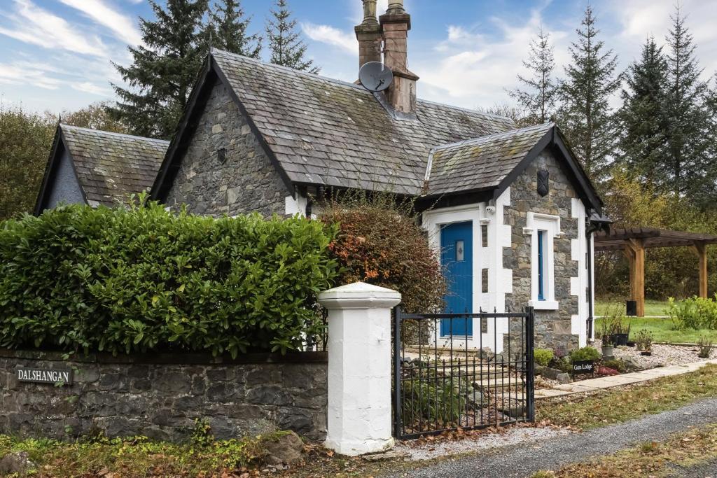 a small stone house with a blue door at Gate Lodge in Castle Douglas