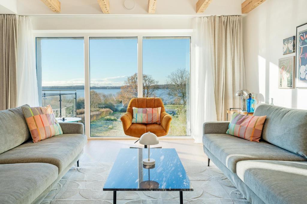 a living room with couches and a chair and a large window at Gollings am See Loft-Suite in Bosau
