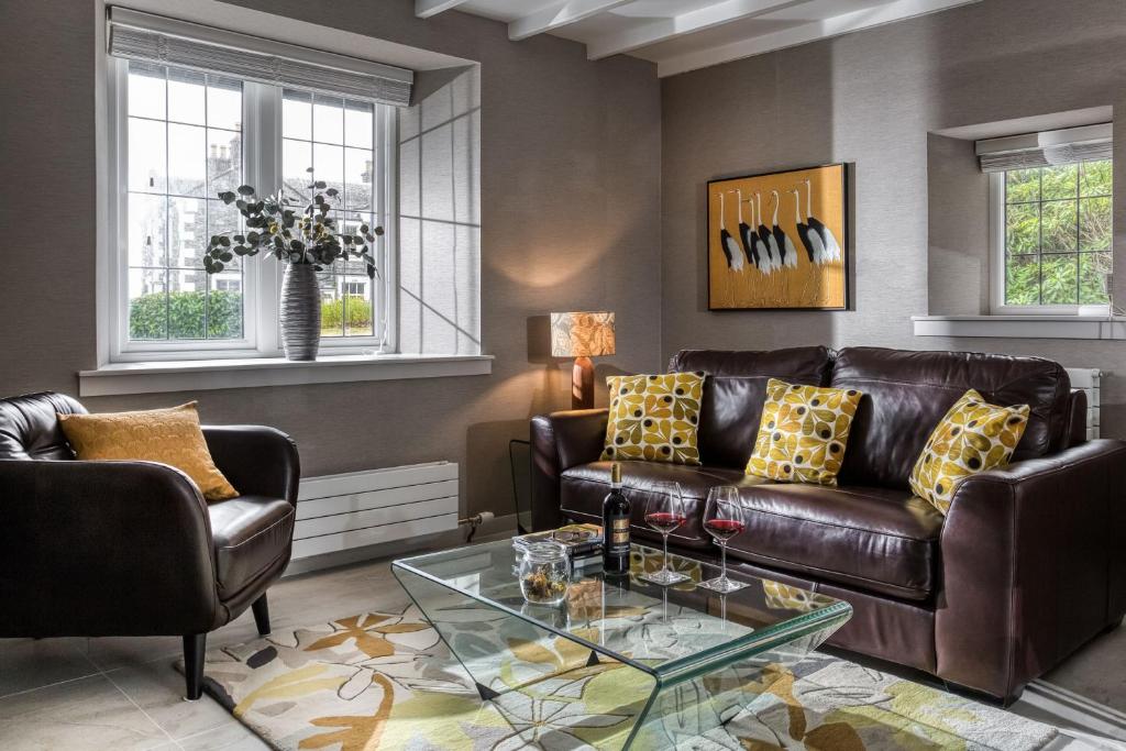 a living room with a leather couch and a glass table at Courtyard Cottage in Castle Douglas