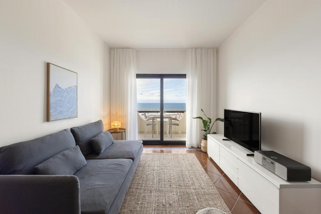 een woonkamer met een bank en een tv bij Pérola do Mar in Foz do Arelho