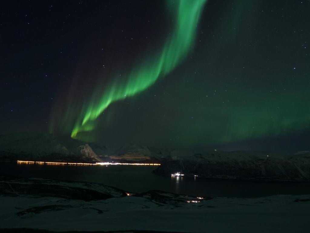 an aurora in the sky over a body of water at Lyngen accommodation and sauna in Lyngseidet