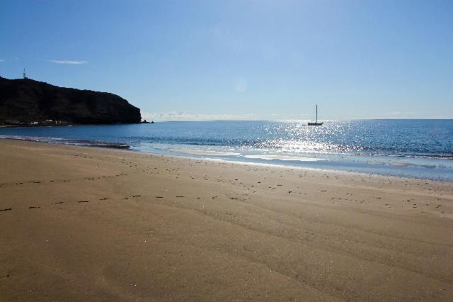 an empty beach with a boat in the water at Apartamento Atis Tirma in Gran Tarajal