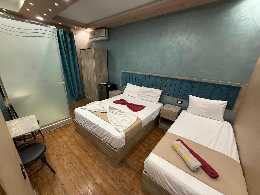 Una pequeña habitación con dos camas y una silla. en The-Cairo Plazario Downtown Hotel, en El Cairo