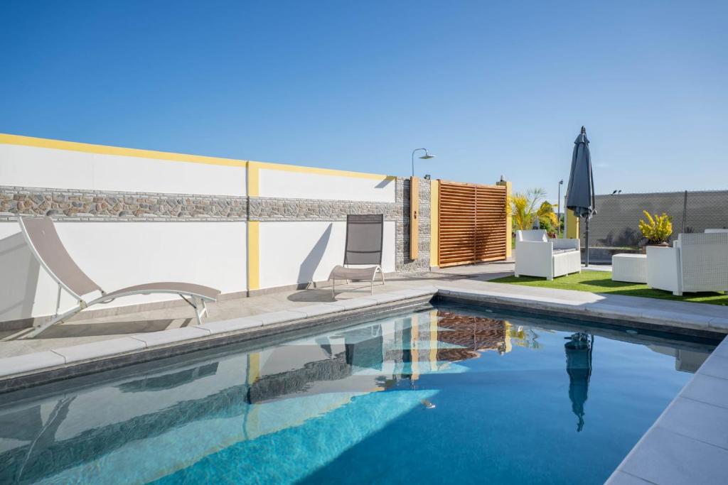 a swimming pool with two chairs and a house at Villa Guenaslo 1 in Saint-François