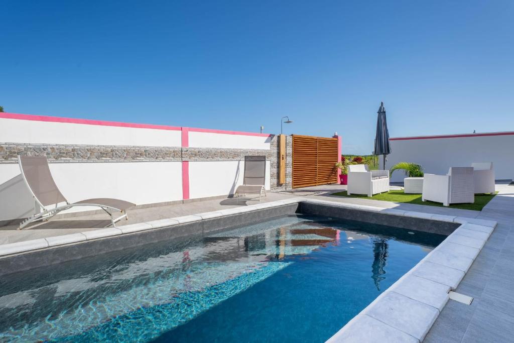 a swimming pool with two chairs and an umbrella at Villa Guenaslo 2 in Saint-François