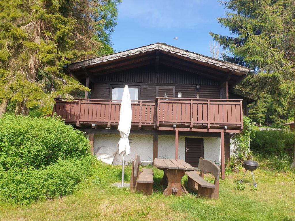 a house with a table and a umbrella and a grill at Ferienhaus Bärenloch in Hilders