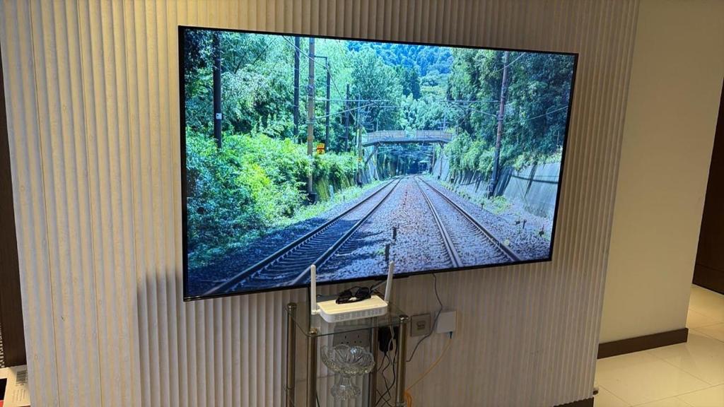 a television hanging on a wall with a picture of a train at Apartment suite in Manama