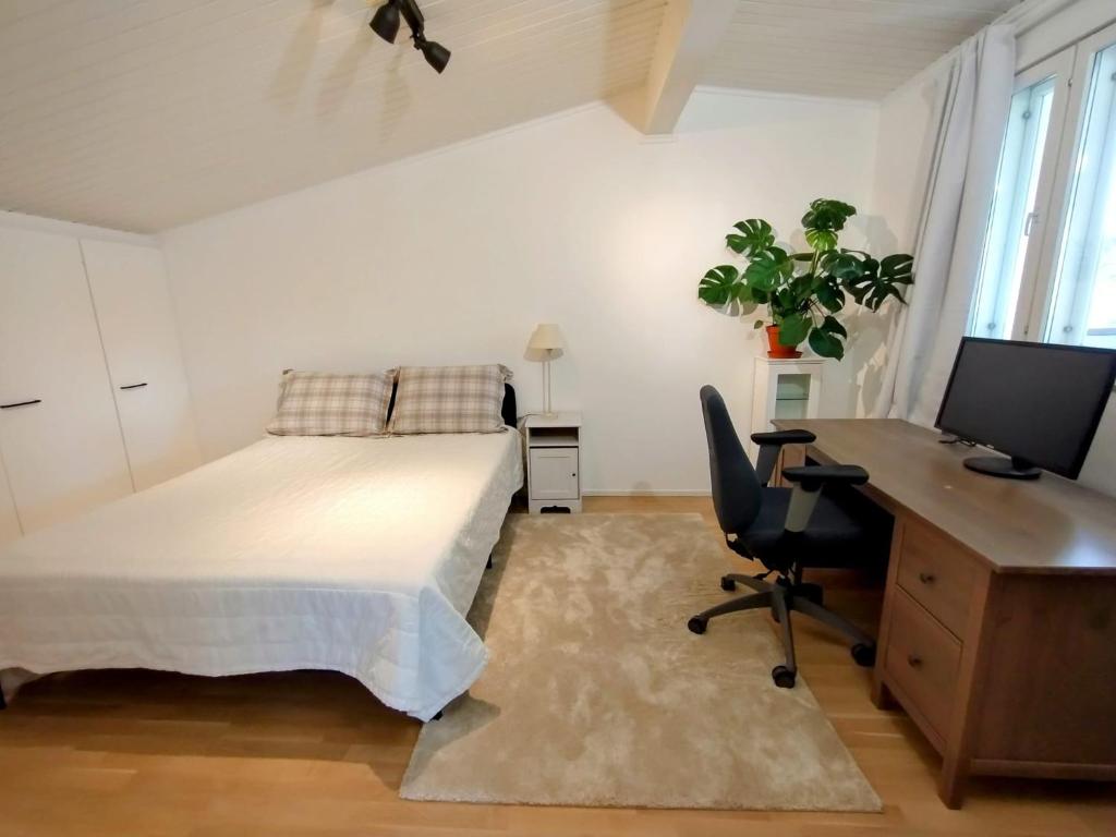 a bedroom with a bed and a desk with a computer at Huone lintukodossa in Helsinki