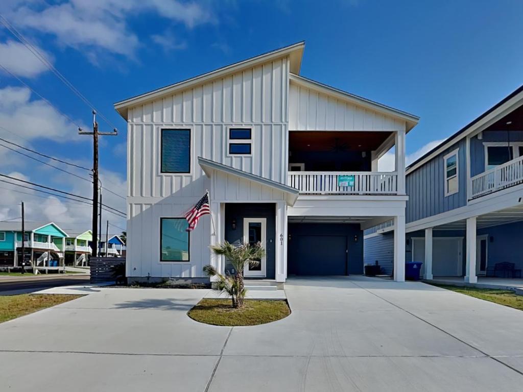 a large white house with an american flag at Serenity At Port A in Port Aransas