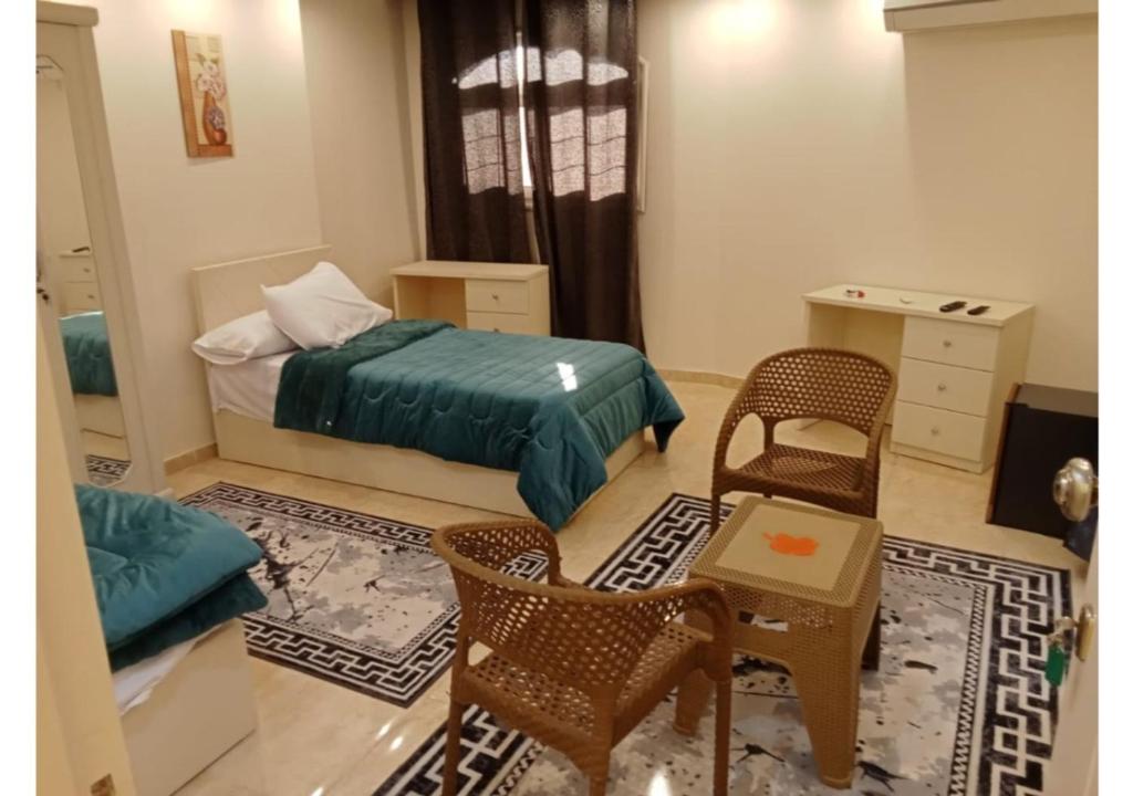 a bedroom with a bed and chairs and a table at رويال للغرف الفندقية in Mît Khamîs
