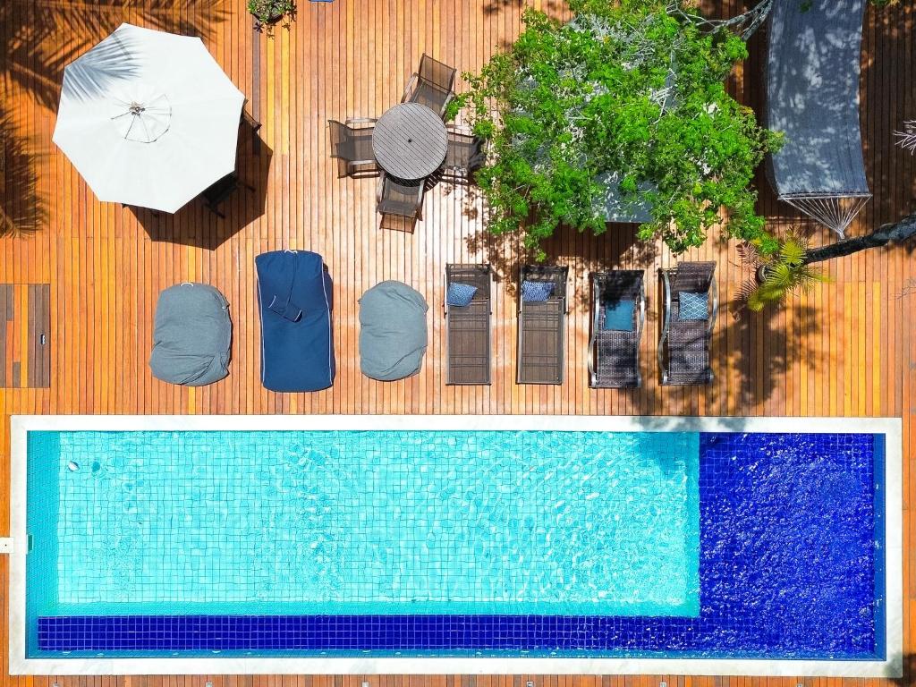an overhead view of a swimming pool with an umbrella and chairs at Villa Maritaca Condomínio de 4 Casas de Locação por Temporada de Alto Padrão com SPA in Arraial d'Ajuda