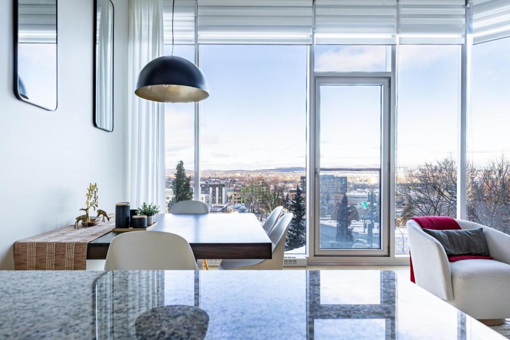een woonkamer met een tafel en stoelen en een groot raam bij Les Immeubles Charlevoix - Le 760-108 in Québec
