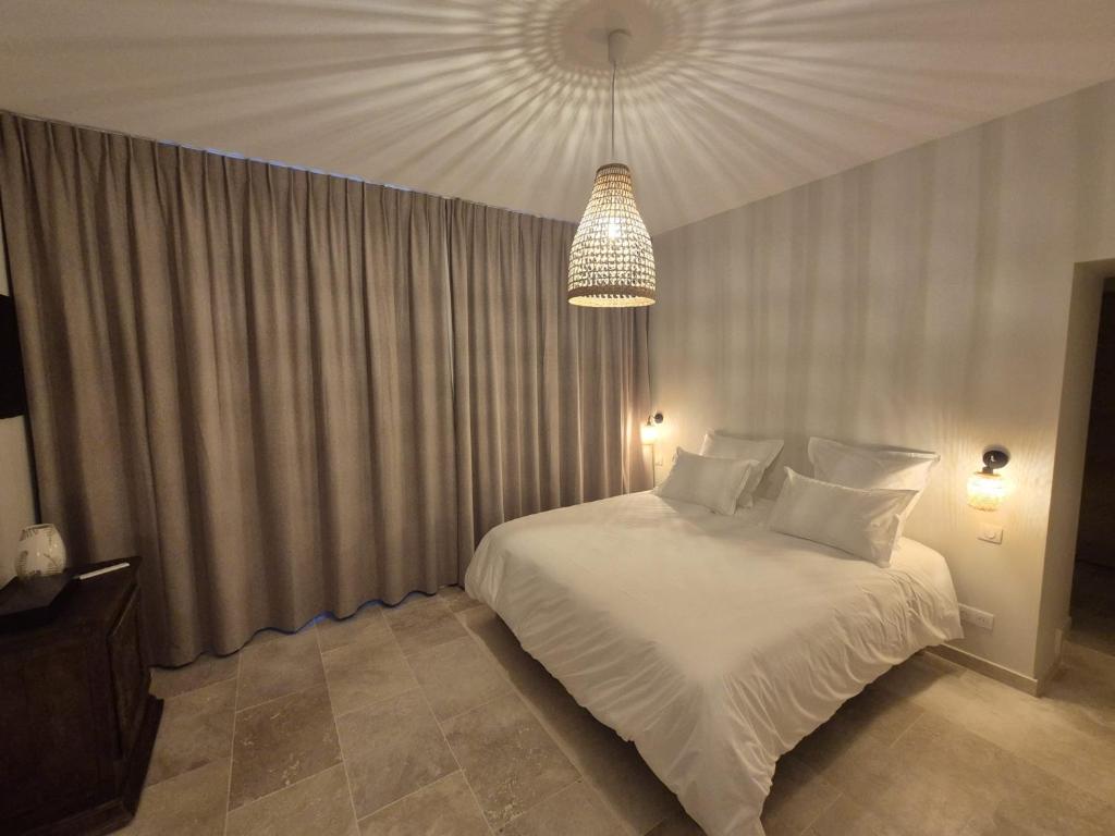 ピエールフォンにあるChâteau de la Follie Le Halloyの白いベッドとシャンデリアのある寝室