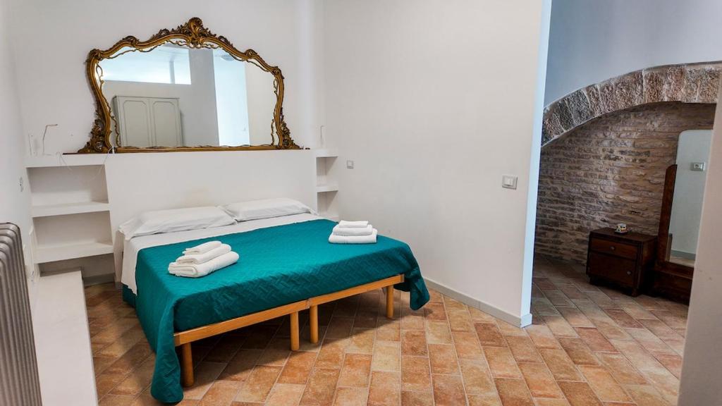 een slaapkamer met een bed met een spiegel aan de muur bij The Gualdo Hideaway in Gualdo Tadino