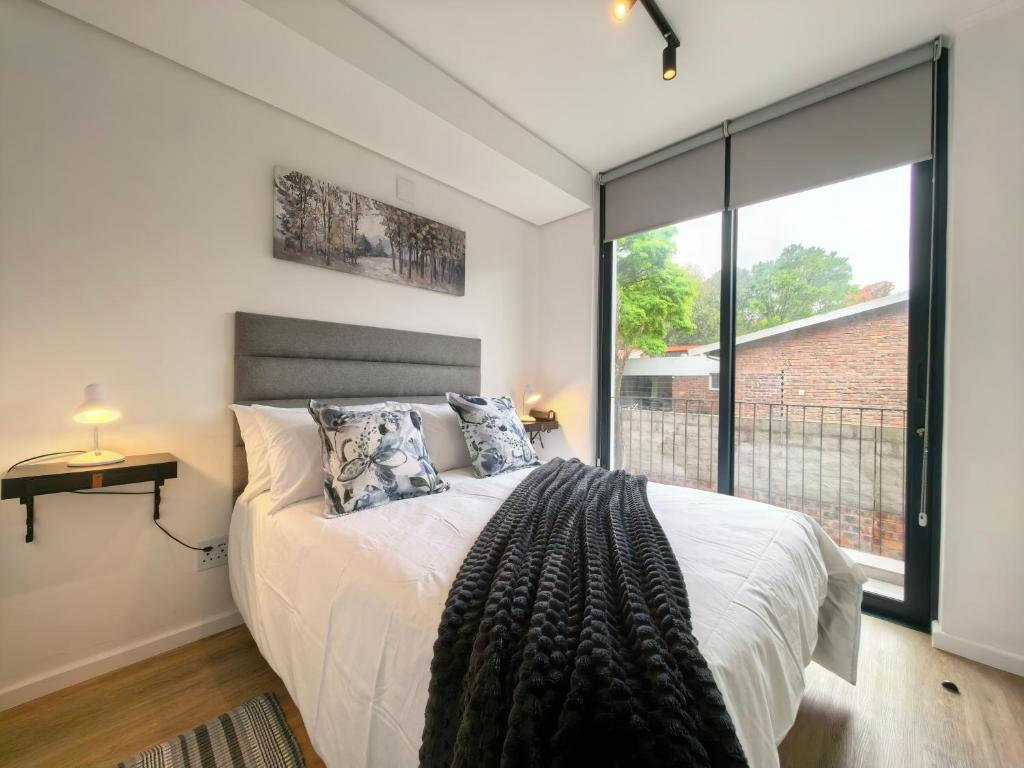 a bedroom with a bed and a large window at Luxury Apartment Unit 111 Le Jardin in George