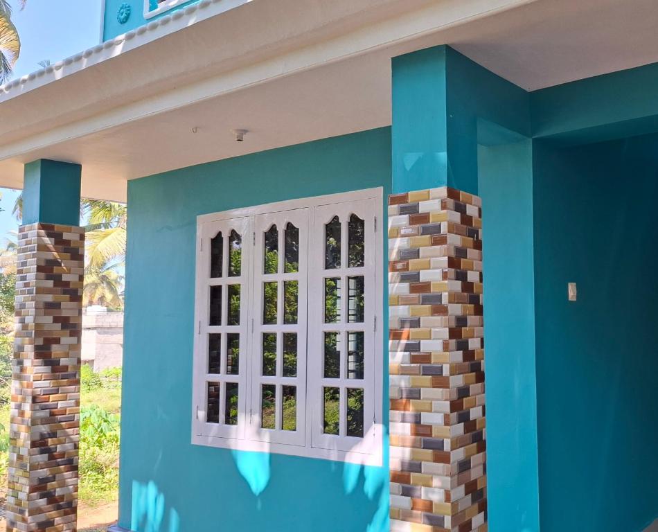 een blauwe muur met een raam op een huis bij Casa Tangerina in Varkala