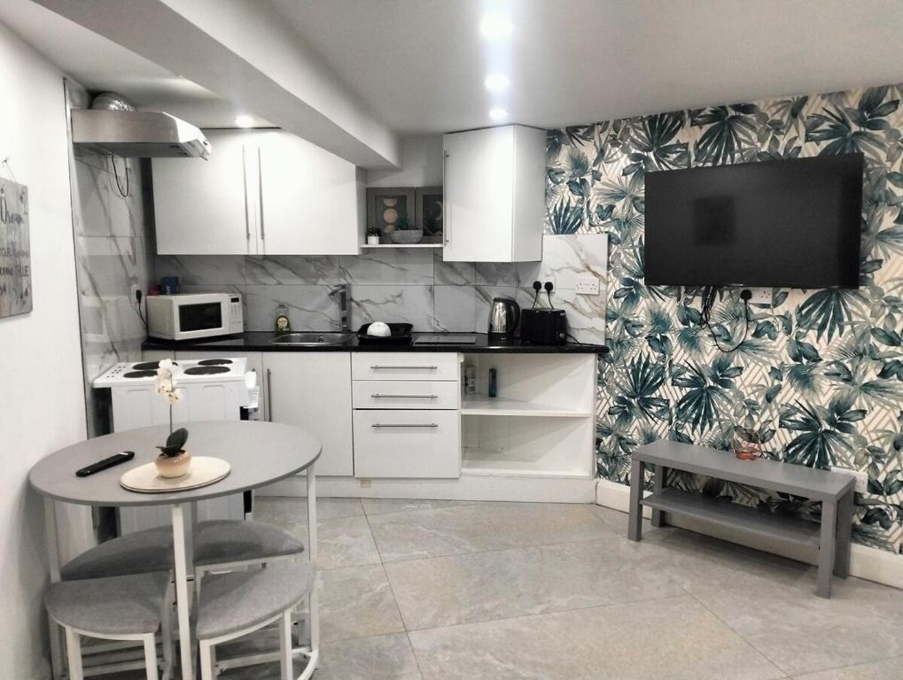 a kitchen with a table and a tv on the wall at Modern 3-bed Serviced Appartement - Milnsbridge in Lindley
