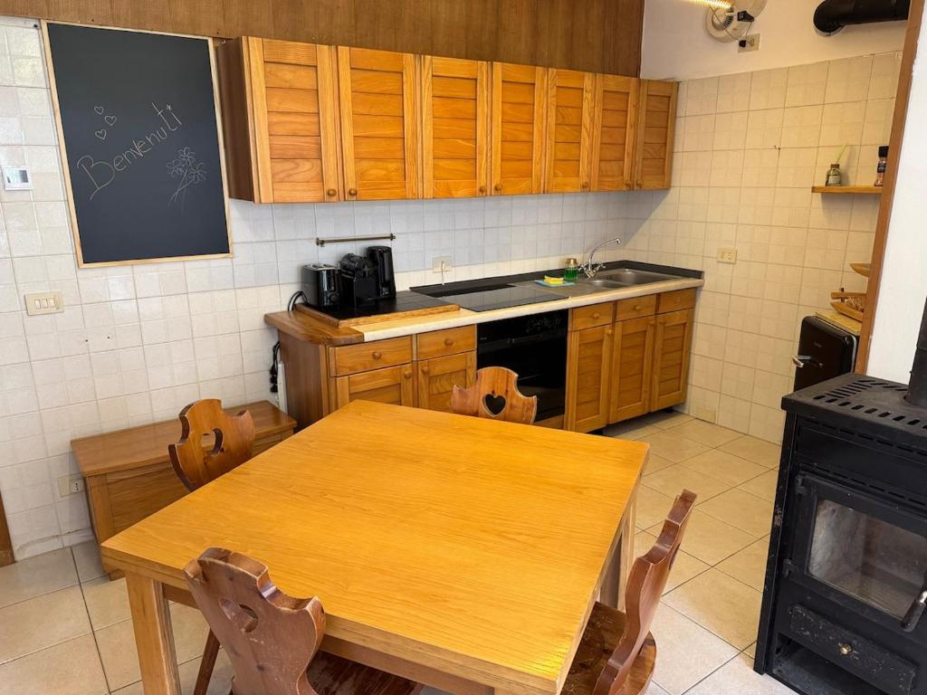 Dolomiti Dream House في سنسنيجا: مطبخ مع طاولة خشبية ودواليب خشبية