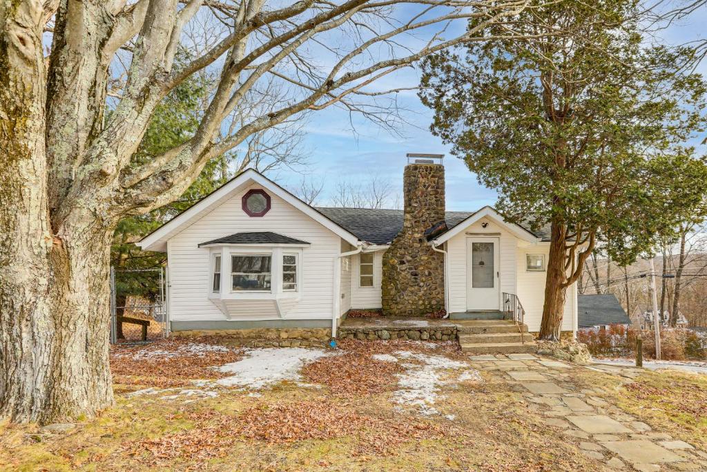 a white house with a chimney and trees at Home with Lake Views and Deck in New Jersey Highlands! in Stanhope