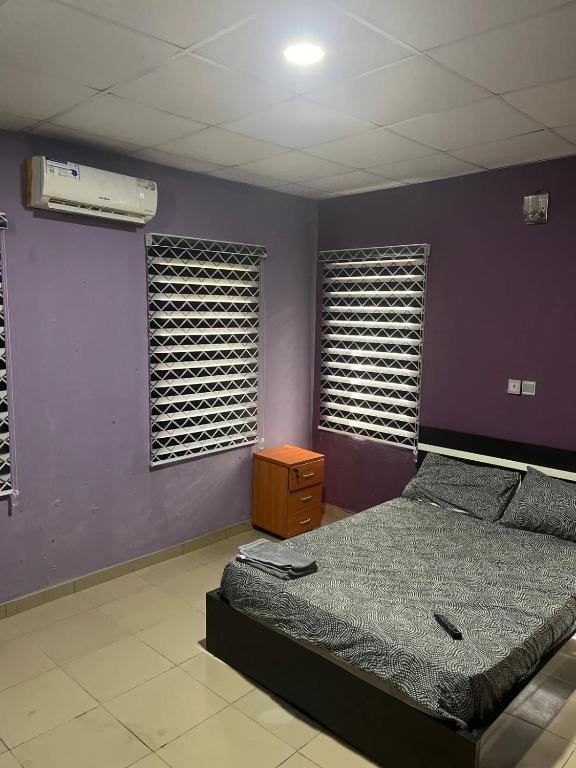 Egbeda vics guests house的一间带床和紫色墙壁的卧室