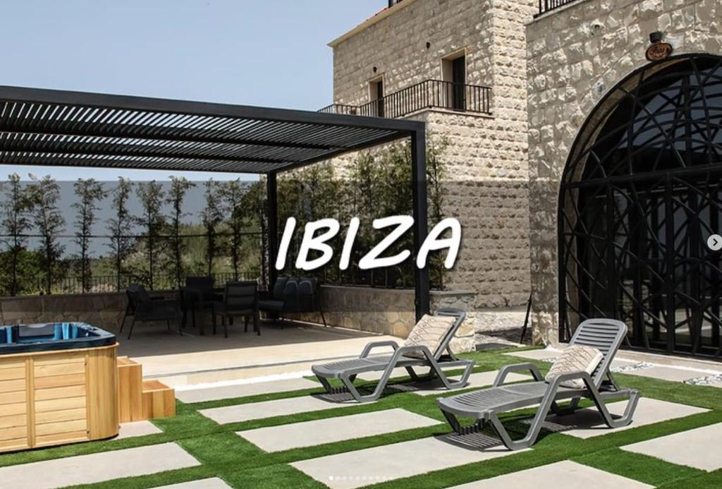 a group of chairs sitting in the grass next to a building at Ibiza in Batroûn